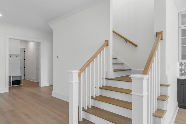 stairway with hardwood / wood-style floors and ornamental molding