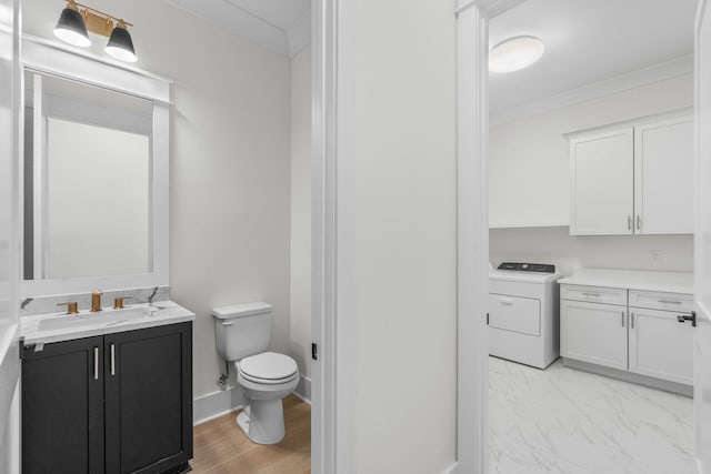 bathroom featuring toilet, vanity, ornamental molding, and washer / dryer