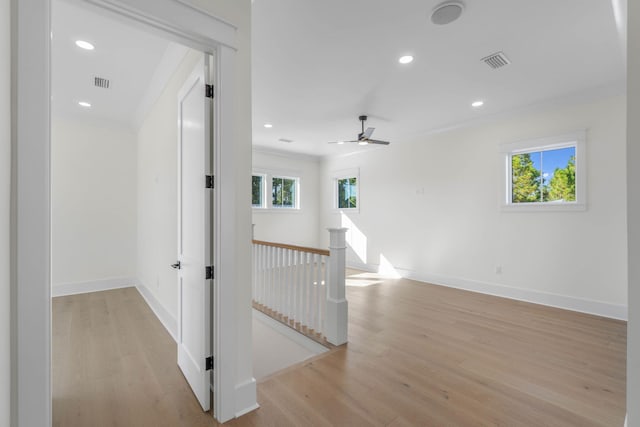 corridor with light wood-type flooring and crown molding