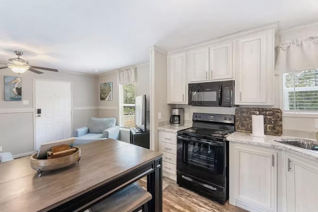 kitchen with light stone countertops, white cabinetry, sink, ceiling fan, and black appliances