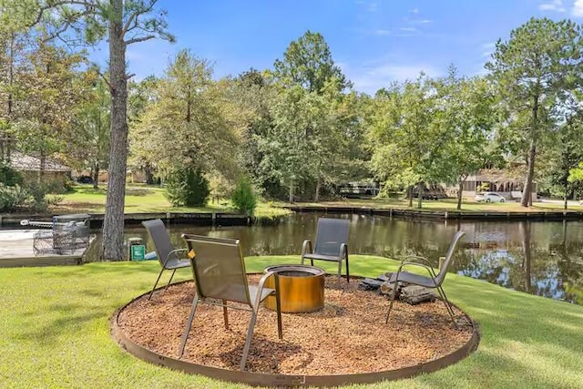 view of community with a fire pit, a water view, and a yard