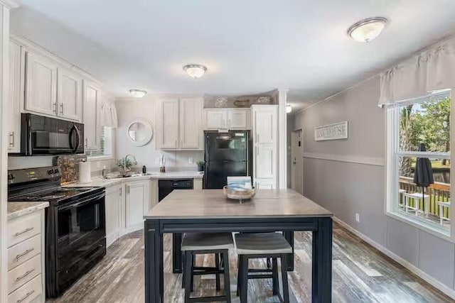 kitchen with black appliances, light hardwood / wood-style floors, white cabinets, and sink