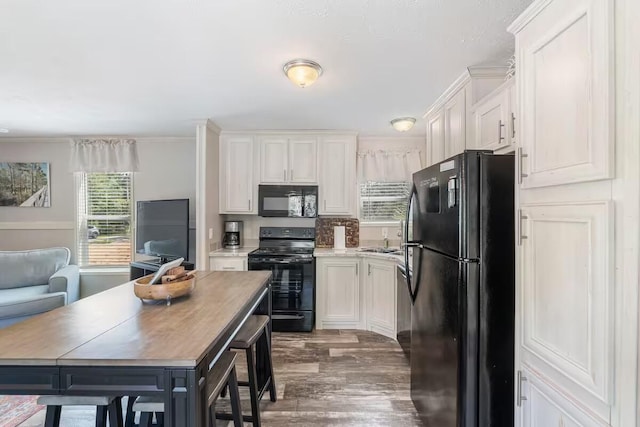 kitchen with white cabinetry, sink, dark wood-type flooring, crown molding, and black appliances