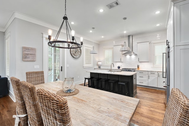 dining space featuring light wood-type flooring, crown molding, a notable chandelier, and sink