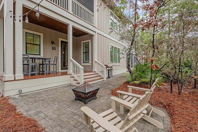 view of patio featuring a balcony and an outdoor fire pit