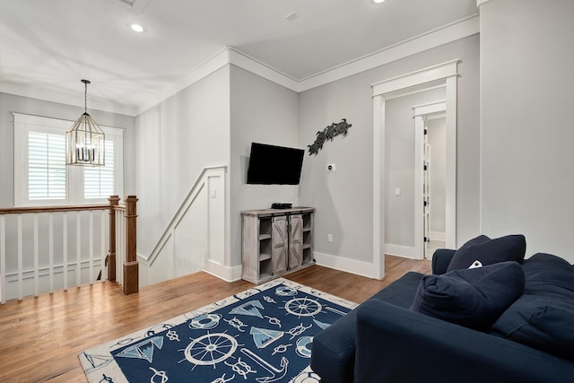 living room featuring hardwood / wood-style flooring, ornamental molding, and an inviting chandelier