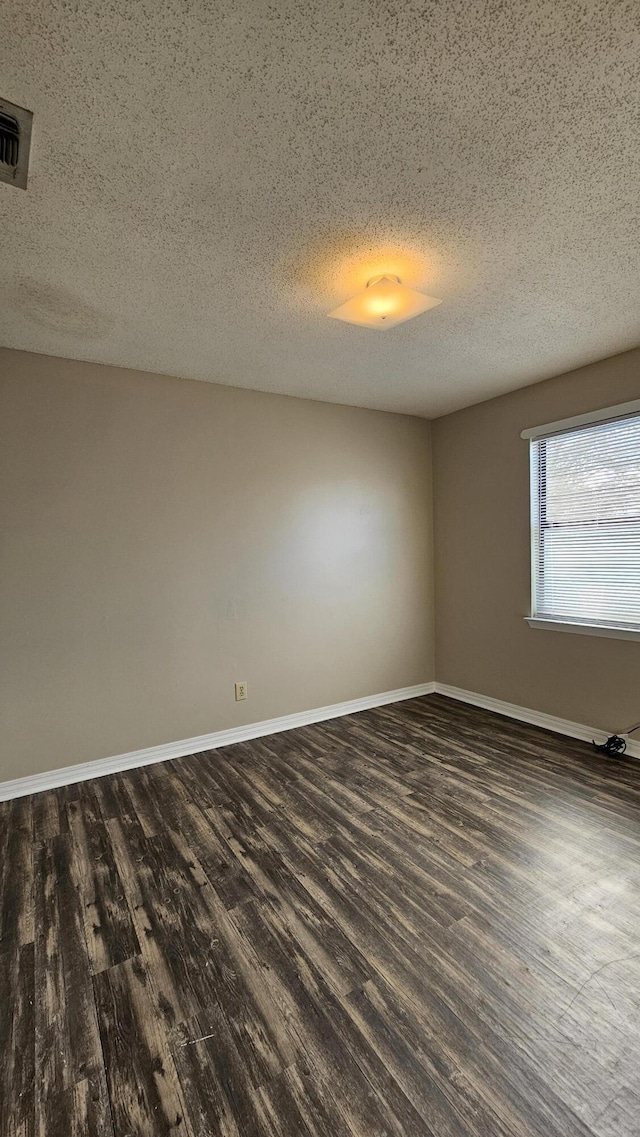 spare room with dark hardwood / wood-style floors and a textured ceiling