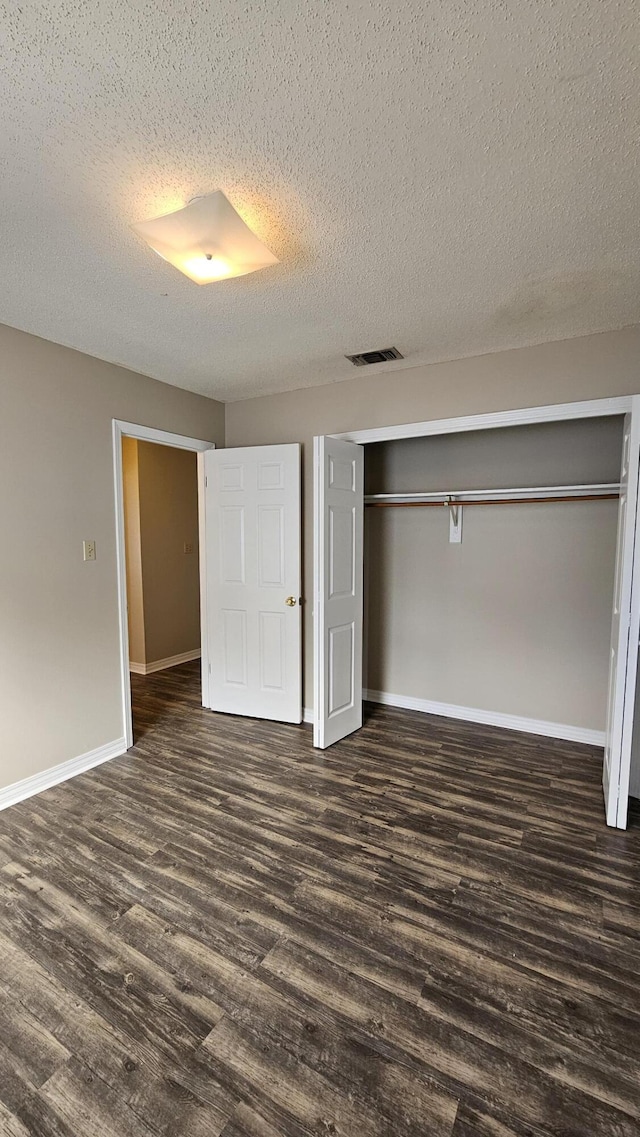 unfurnished bedroom with dark hardwood / wood-style flooring, a closet, and a textured ceiling