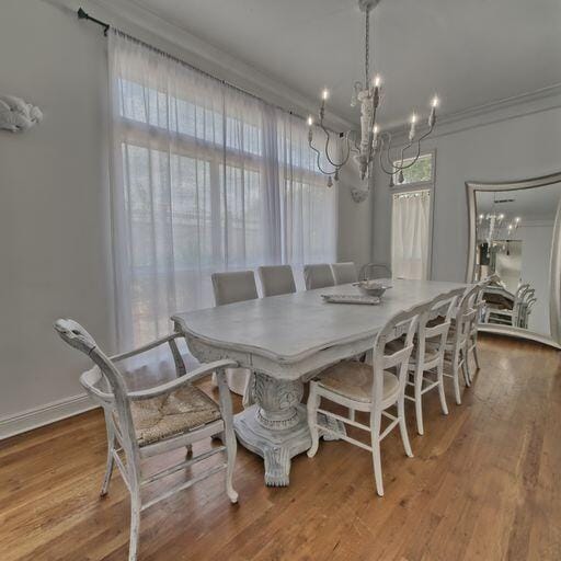 dining room featuring hardwood / wood-style flooring, crown molding, and an inviting chandelier