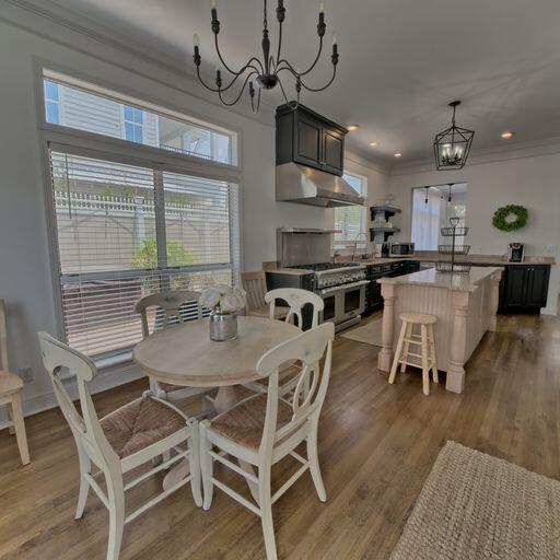 dining room with hardwood / wood-style flooring, crown molding, sink, and an inviting chandelier