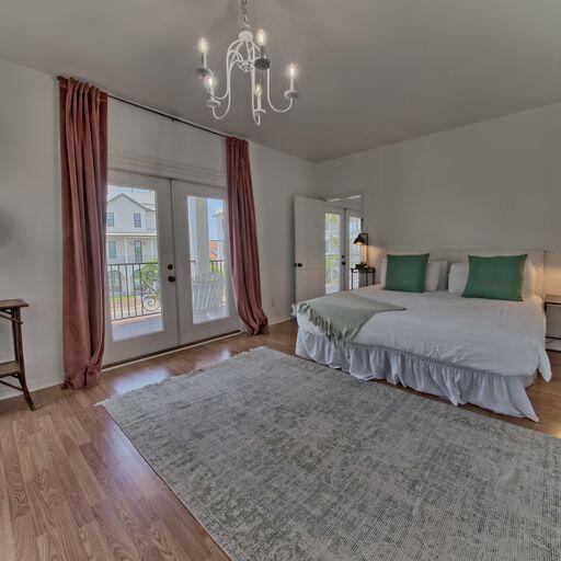 bedroom with access to exterior, french doors, light hardwood / wood-style floors, and an inviting chandelier