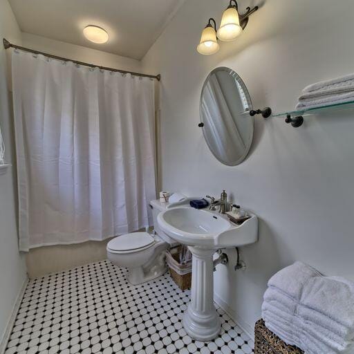 bathroom with tile patterned floors, shower / bath combo with shower curtain, and toilet