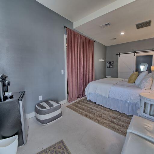 bedroom featuring a barn door and concrete flooring