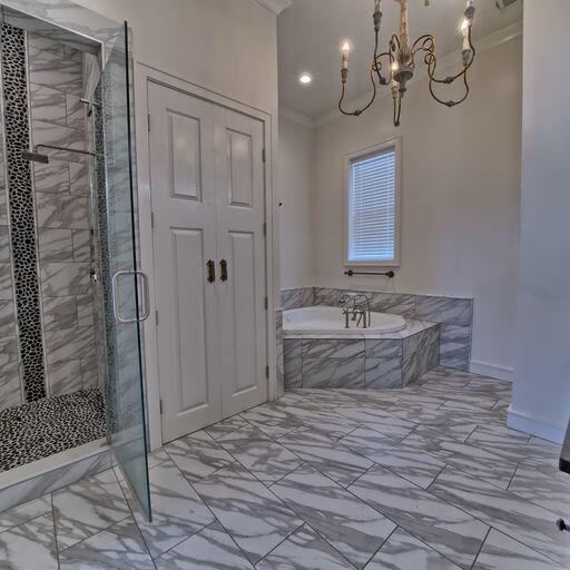 bathroom with shower with separate bathtub, an inviting chandelier, and ornamental molding