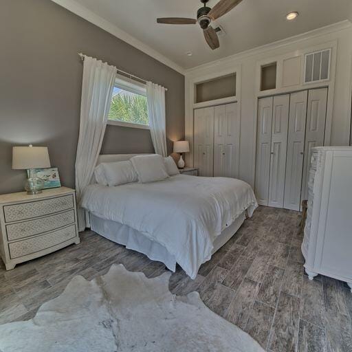 bedroom featuring ceiling fan, crown molding, and two closets