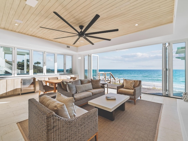 tiled living room featuring wood ceiling, a water view, a beach view, and ceiling fan