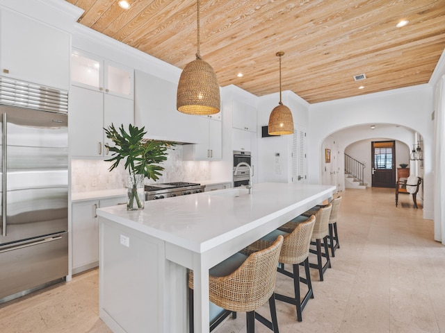 kitchen featuring stainless steel appliances, a kitchen island with sink, pendant lighting, and wooden ceiling