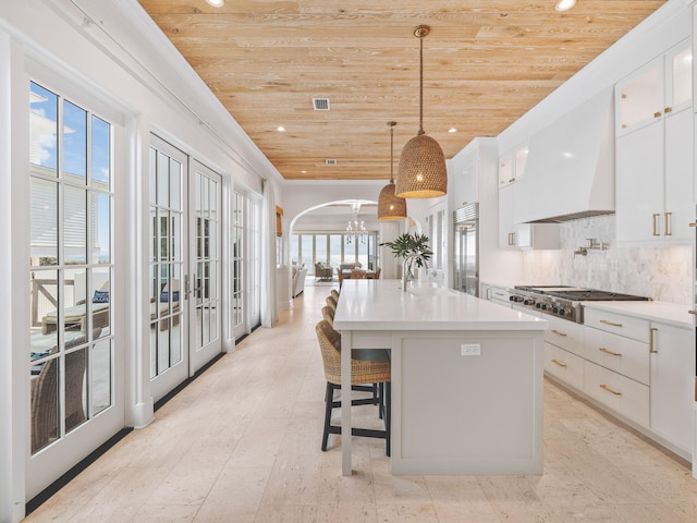 kitchen featuring hanging light fixtures, stainless steel appliances, white cabinets, a center island with sink, and wooden ceiling