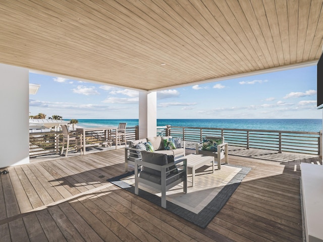 wooden terrace featuring a water view, outdoor lounge area, and a beach view