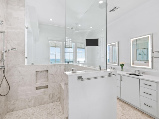 bathroom with crown molding, tiled shower, and vanity