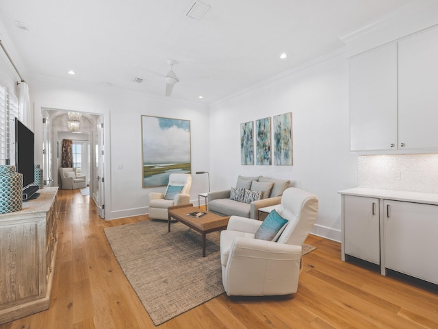 living room featuring light hardwood / wood-style flooring, ornamental molding, and ceiling fan