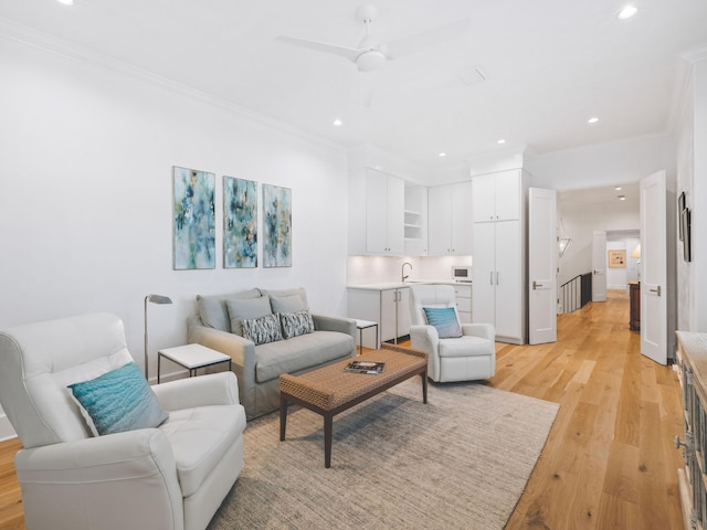 living room featuring crown molding, ceiling fan, and light hardwood / wood-style flooring