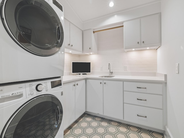 laundry room with sink, cabinets, and stacked washer / dryer