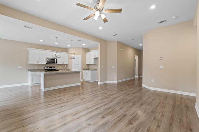 unfurnished living room featuring ceiling fan, sink, and light hardwood / wood-style floors