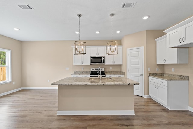 kitchen featuring white cabinets, a kitchen island with sink, appliances with stainless steel finishes, and sink