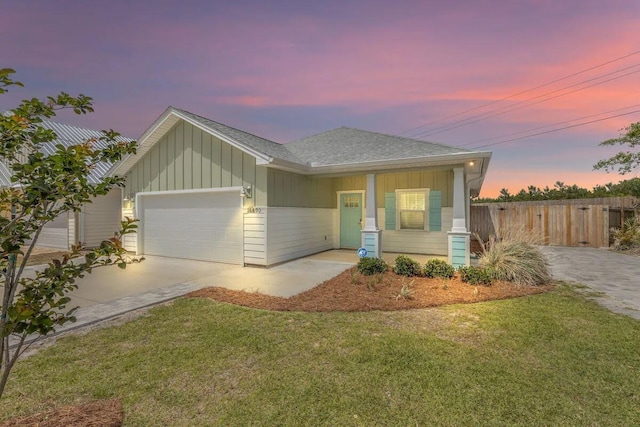 view of front of property with a porch, a yard, and a garage