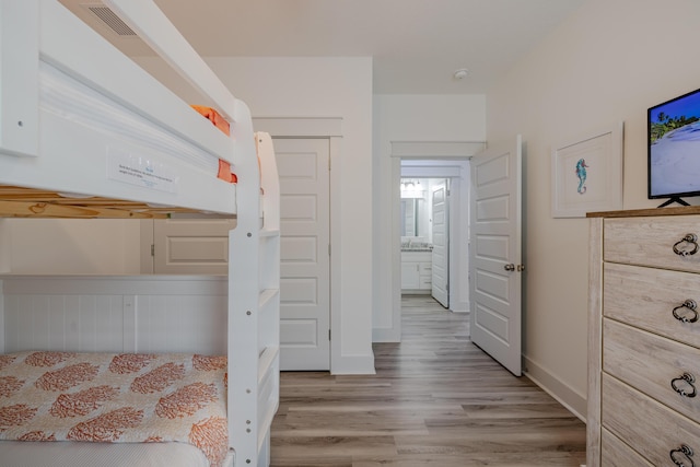 unfurnished bedroom featuring ensuite bath and light wood-type flooring