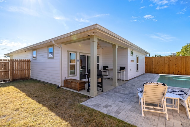 rear view of house featuring ceiling fan, a patio area, and a lawn