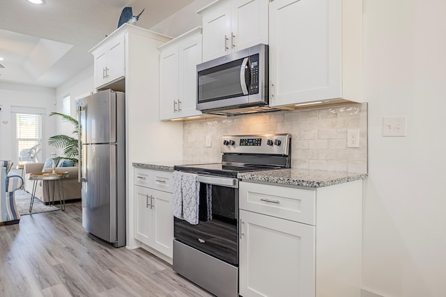 kitchen with stainless steel appliances, light hardwood / wood-style flooring, white cabinetry, and a tray ceiling