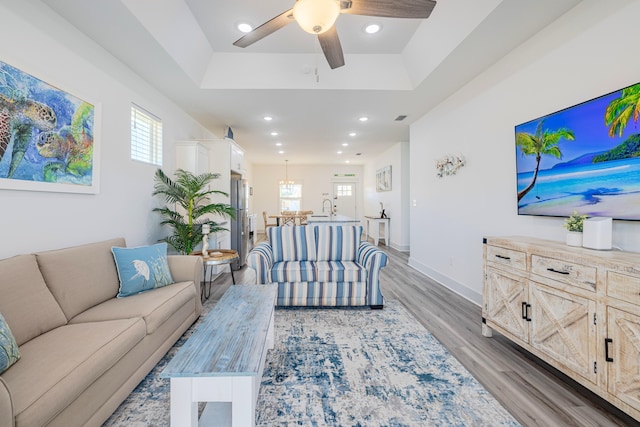 living room with light hardwood / wood-style floors, sink, a raised ceiling, and a healthy amount of sunlight