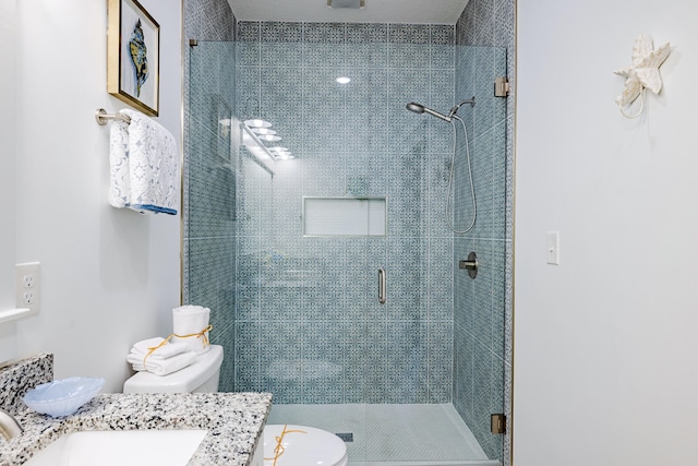 bathroom featuring a shower with door, toilet, and vanity