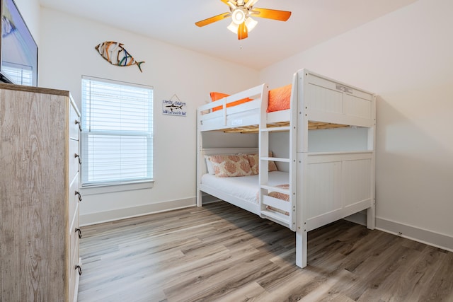 unfurnished bedroom with ceiling fan, wood-type flooring, and multiple windows