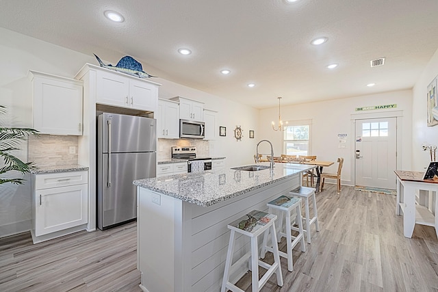 kitchen with tasteful backsplash, sink, light wood-type flooring, stainless steel appliances, and white cabinets