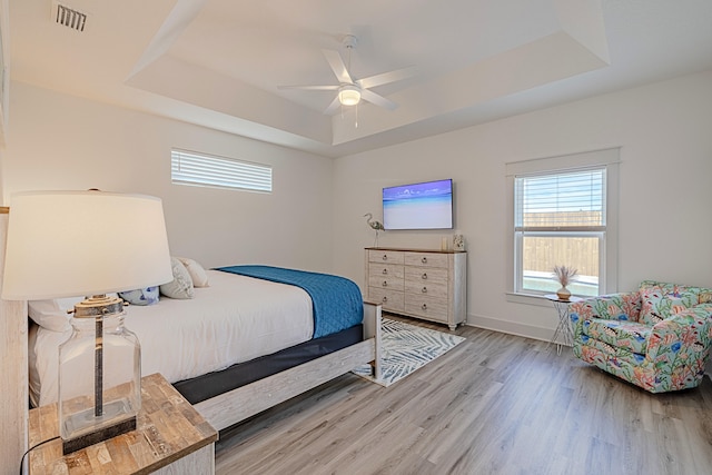 bedroom with ceiling fan, hardwood / wood-style floors, and a raised ceiling