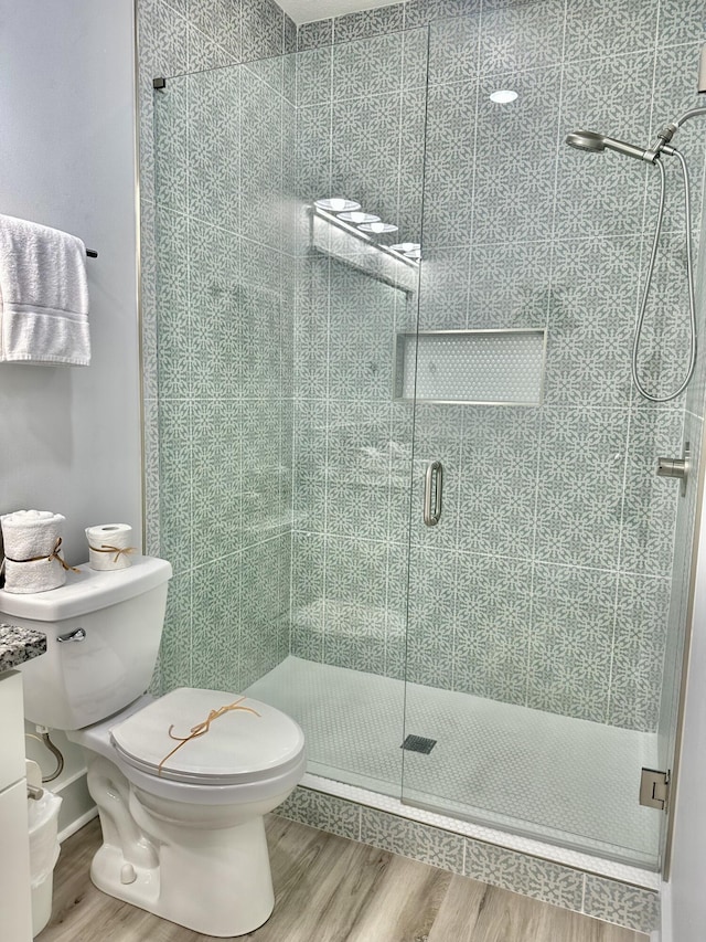 21400 Marlin Ave, Panama City Beach, FL 32413 - bathroom featuring wood finished floors, toilet, and a stall shower