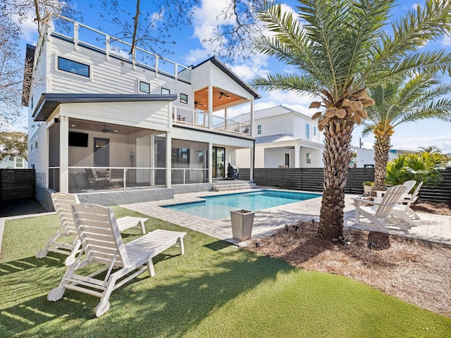 view of swimming pool featuring a lawn, a sunroom, ceiling fan, and a patio area