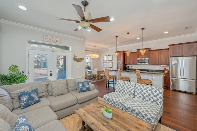 living room with ceiling fan with notable chandelier, ornamental molding, dark wood-type flooring, and french doors