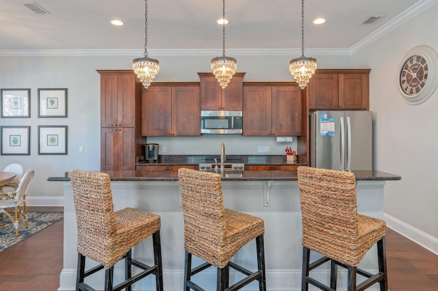 kitchen featuring a kitchen breakfast bar, a kitchen island with sink, crown molding, and appliances with stainless steel finishes