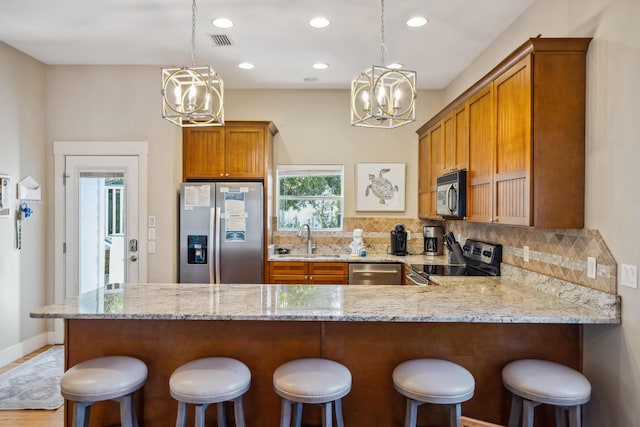 kitchen with appliances with stainless steel finishes, sink, a kitchen breakfast bar, kitchen peninsula, and a chandelier