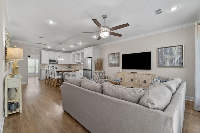 living room featuring ceiling fan, ornamental molding, and hardwood / wood-style flooring