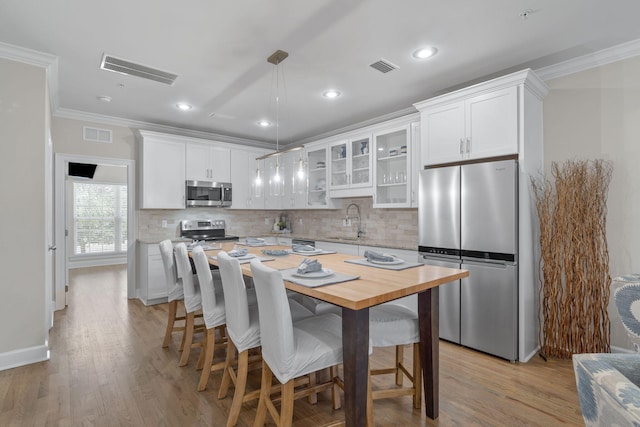 kitchen with white cabinetry, sink, stainless steel appliances, pendant lighting, and a kitchen island