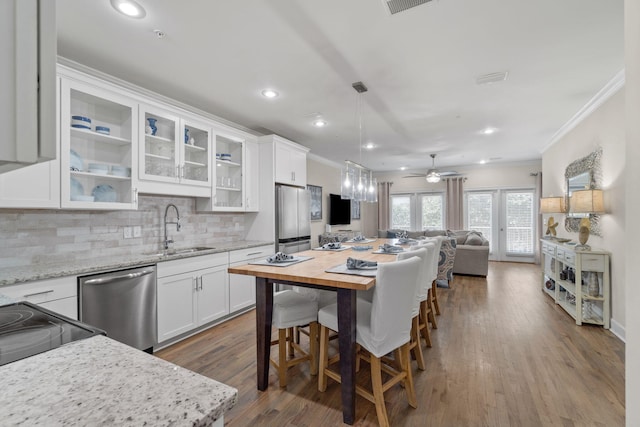 kitchen with light stone countertops, appliances with stainless steel finishes, ceiling fan, sink, and white cabinetry