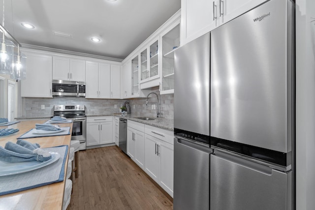 kitchen with dark hardwood / wood-style flooring, stainless steel appliances, sink, decorative light fixtures, and white cabinets