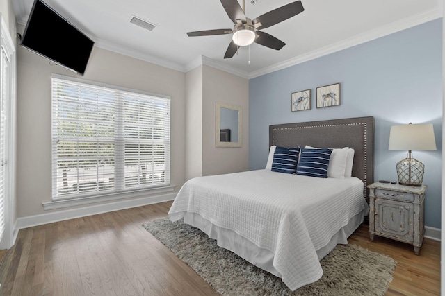 bedroom with hardwood / wood-style floors, ceiling fan, and crown molding