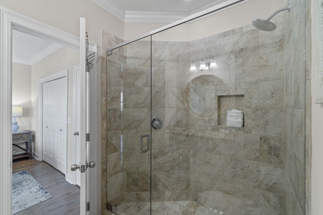 bathroom with wood-type flooring, a shower with shower door, and ornamental molding