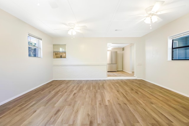 empty room featuring light wood-style floors, visible vents, ceiling fan, and baseboards